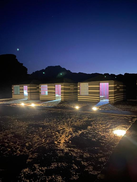 DisahにあるRed Twilight Campの夜間のピンクと白のドアが施された木造の建物