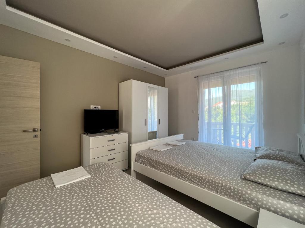 1 dormitorio con 2 camas, TV y ventana en Mavalux apartments en Tivat