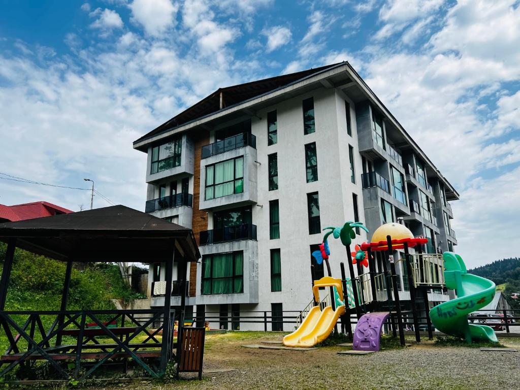 un edificio con parque infantil frente a un edificio en BOBLINE BAKURIANI SUITE, en Bakuriani