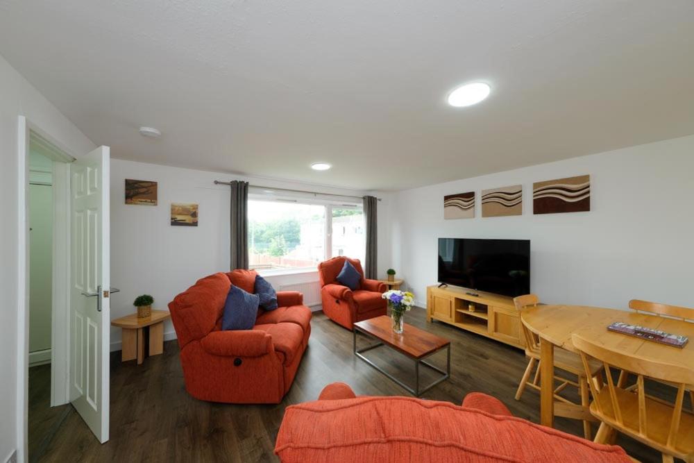 Sala de estar con 2 sillas de color naranja y TV en Premier Apt - Bridge View-Rosyth, en Rosyth