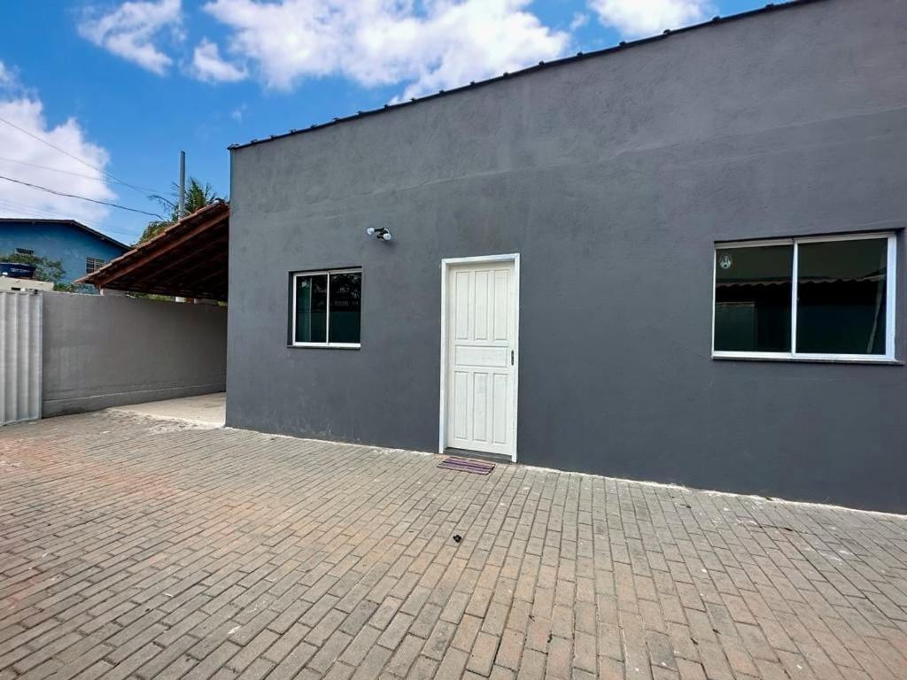 um edifício cinzento com uma porta branca e uma entrada de tijolos em Casa toda - Praia Barra do Sahy - Aracruz em Aracruz