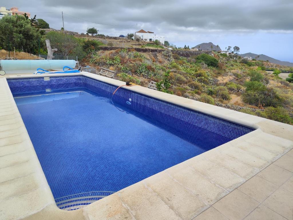 a large blue swimming pool with a hill in the background at LA CASA DEL ALMÁCIGO in Arona