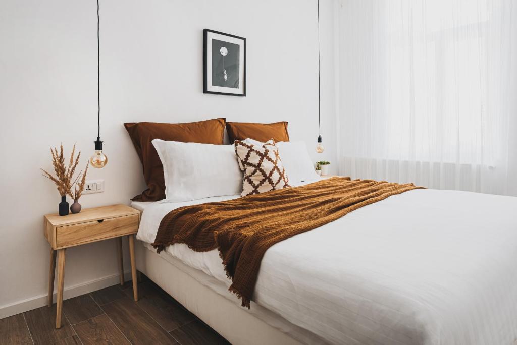 a bedroom with a large bed with a wooden night stand at VOYA NORDIC Apartment-a luxury oasis in the old town in Braşov