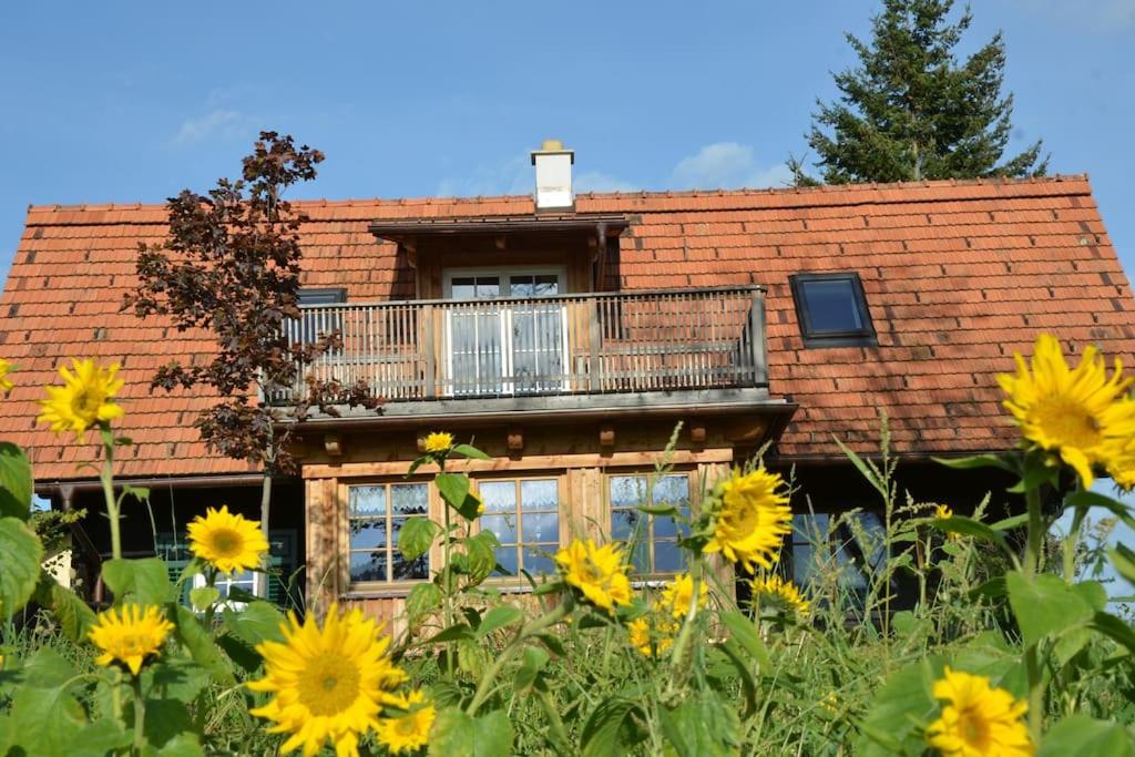 een huis met een balkon en een veld met zonnebloemen bij Sonniges Kellerstöckel im Schilcherland in Deutschlandsberg