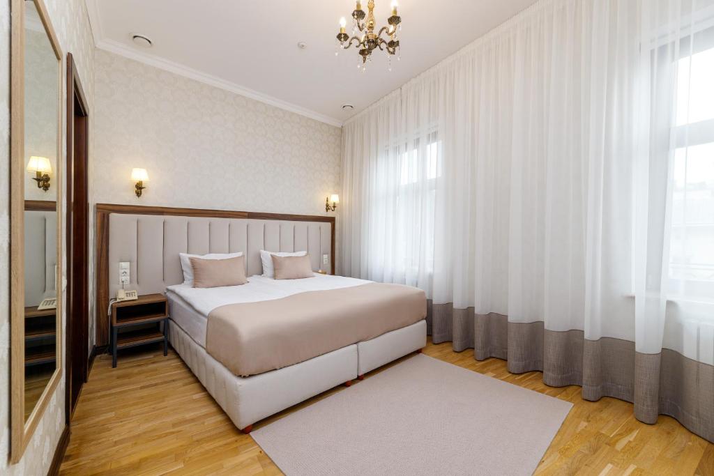 una camera da letto con un grande letto bianco e un lampadario a braccio di Feder Boutique Hotel a Lviv