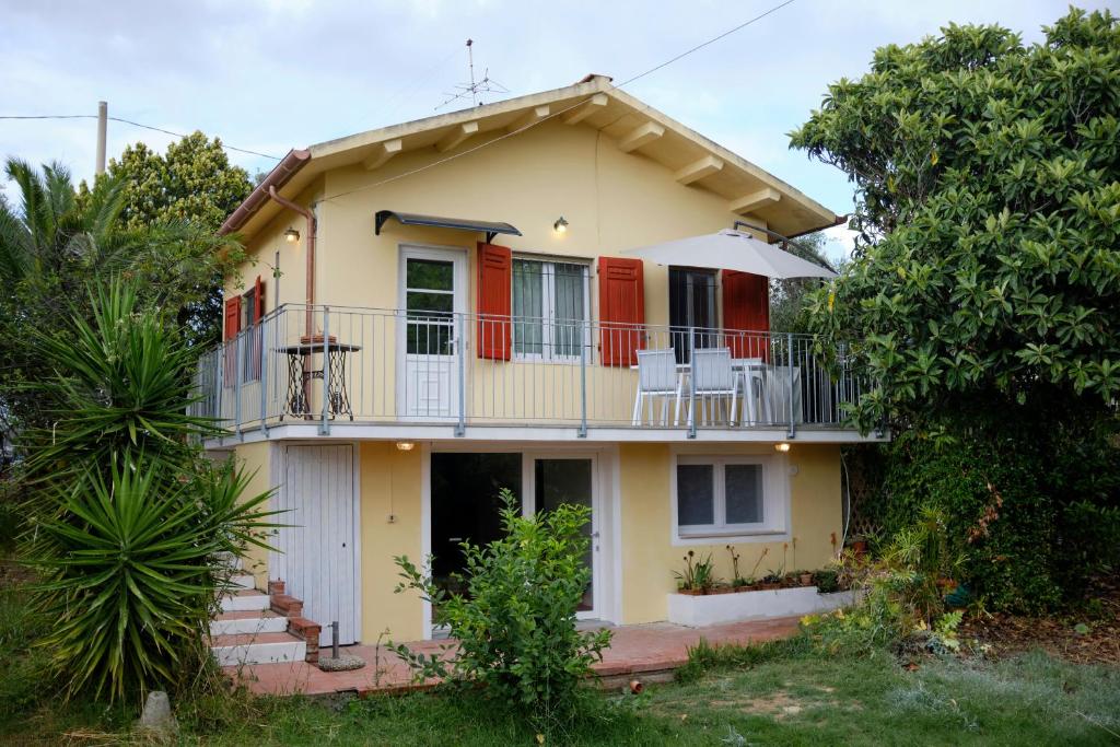 Casa amarilla con balcón con sillas. en Villa Anna Bolgheri, en Bolgheri