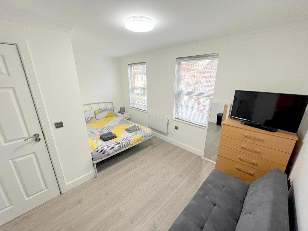 a bedroom with a bed and a tv and a couch at Exeter Road Rooms in South Norwood