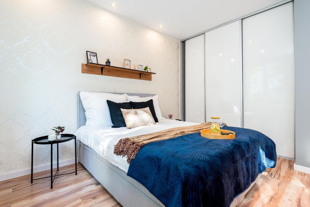 a bedroom with a large bed with a blue blanket at Kairos Apartments - City - darmowy Parking, ścisłe centrum in Katowice