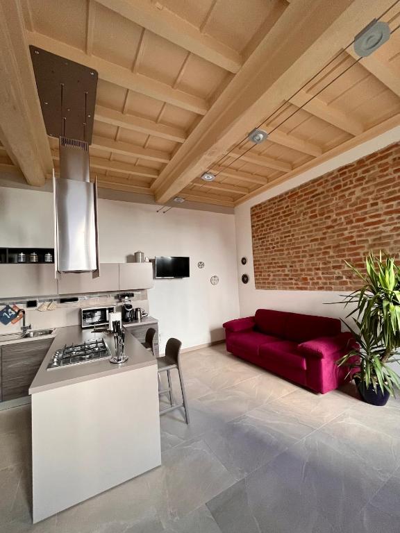 una cucina e un soggiorno con divano rosso di Dimora Boezio7, cozy and charming place in center with private parking a Pavia