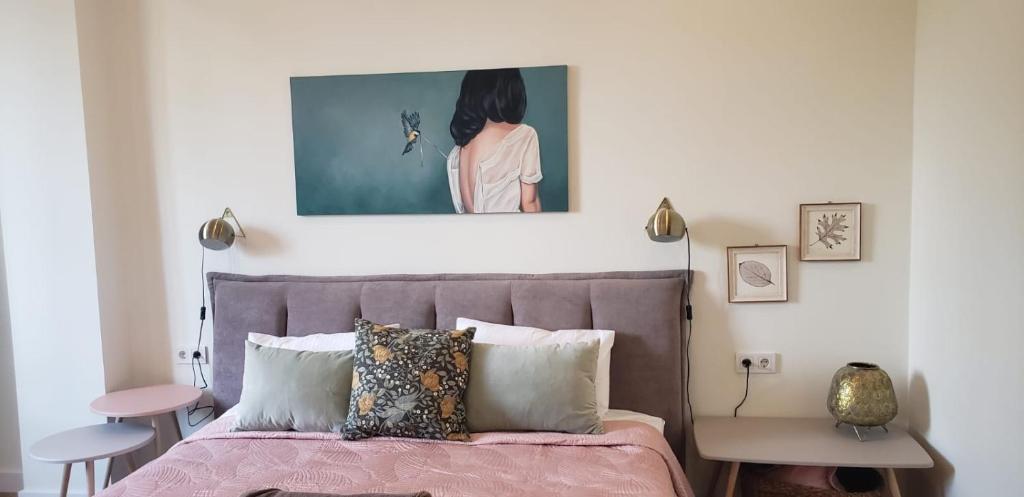 una camera da letto con un letto rosa e un dipinto sopra di esso di Cozy Urban Retreat a Almaty