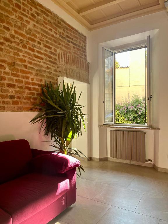 un soggiorno con divano rosso e muro di mattoni di Dimora Boezio7, cozy and charming place in center with private parking a Pavia