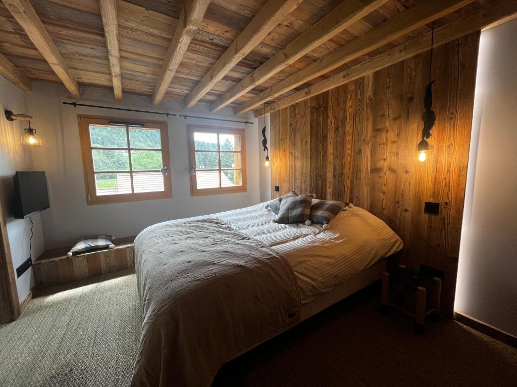 ein Schlafzimmer mit einem Bett in einem Zimmer mit Holzwänden in der Unterkunft Stone Lake Luxury Lodge in Gérardmer