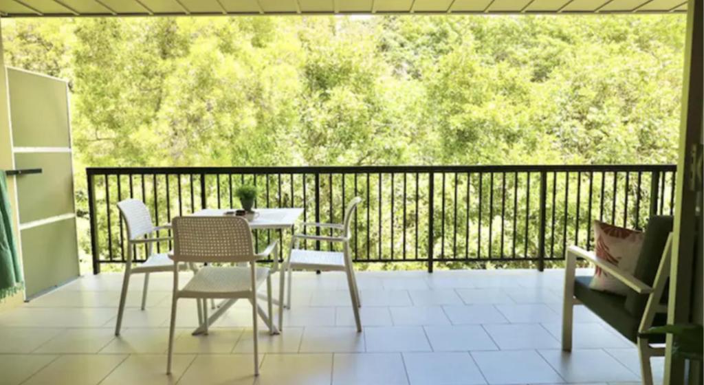 a patio with a table and chairs on a balcony at Tranquil treetop retreat minutes from the beach 7405 in Noosa Heads