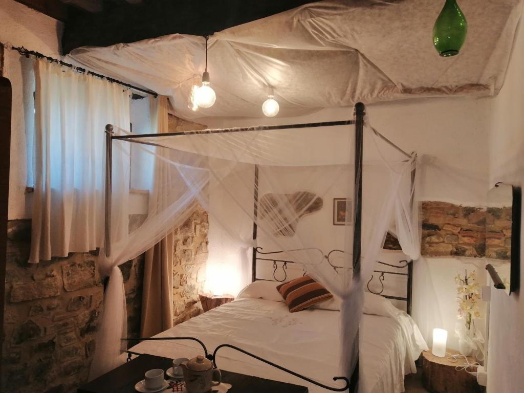- une chambre avec un lit à baldaquin blanc et une table dans l'établissement Vecchio Casale Quercetino - Il forno, à Montenero