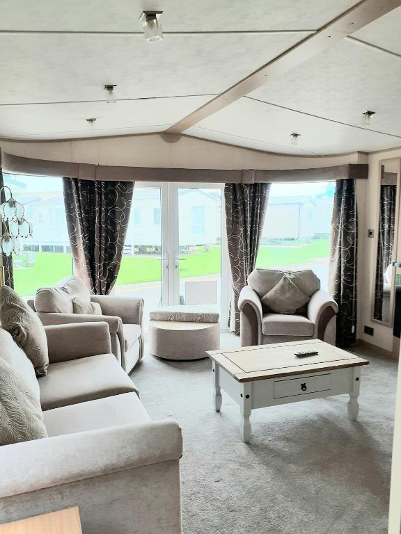 a living room with couches and a coffee table at The James Lodge in Little Clacton