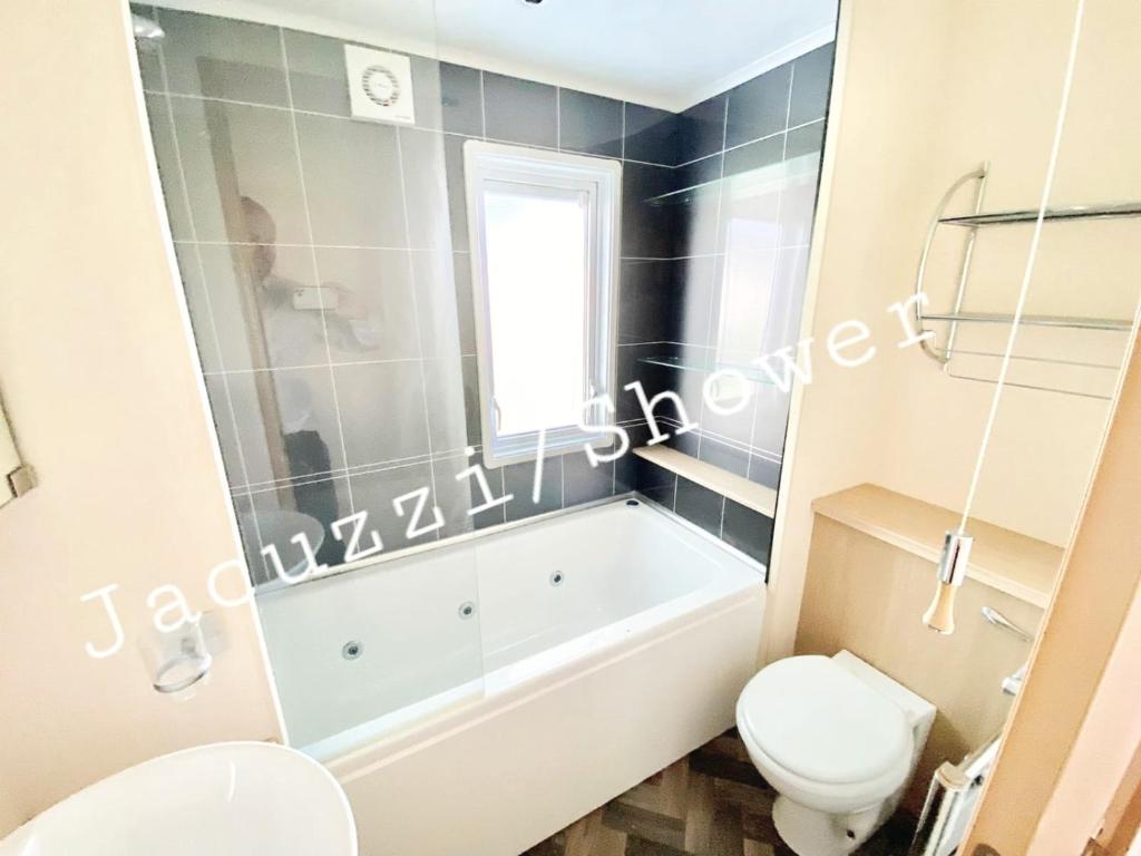 a bathroom with a white tub and a toilet at The James Lodge in Little Clacton