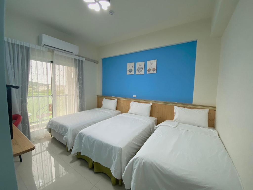 台東市的住宿－好時光電梯民宿，蓝色墙壁客房的两张床