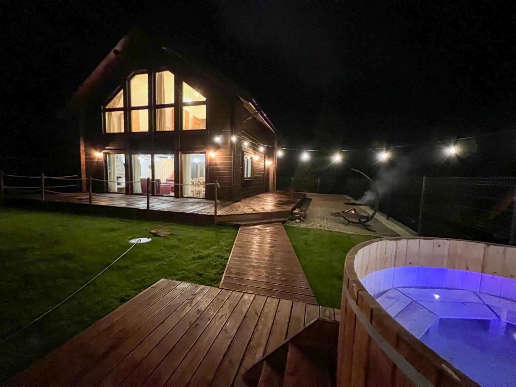 uma casa à noite com um deque e uma banheira de hidromassagem em Marina Olchowiec - Villa em Olchowiec