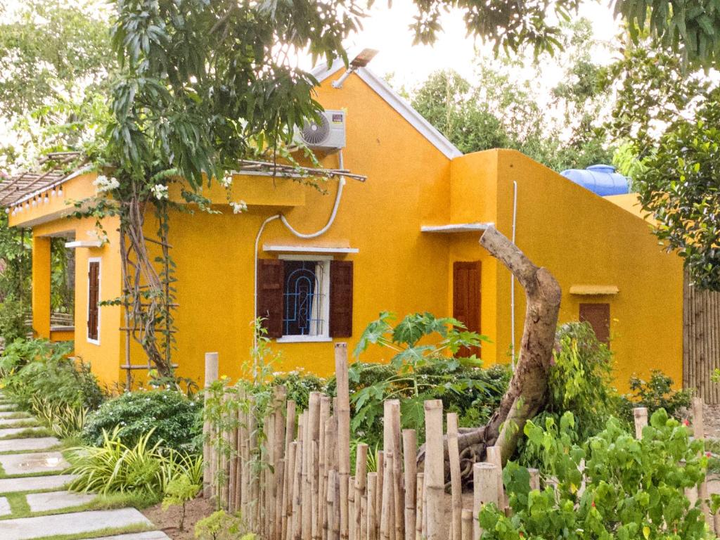 uma casa amarela com uma cerca em frente em Mango House Retreat Quy Nhon em Quy Nhon