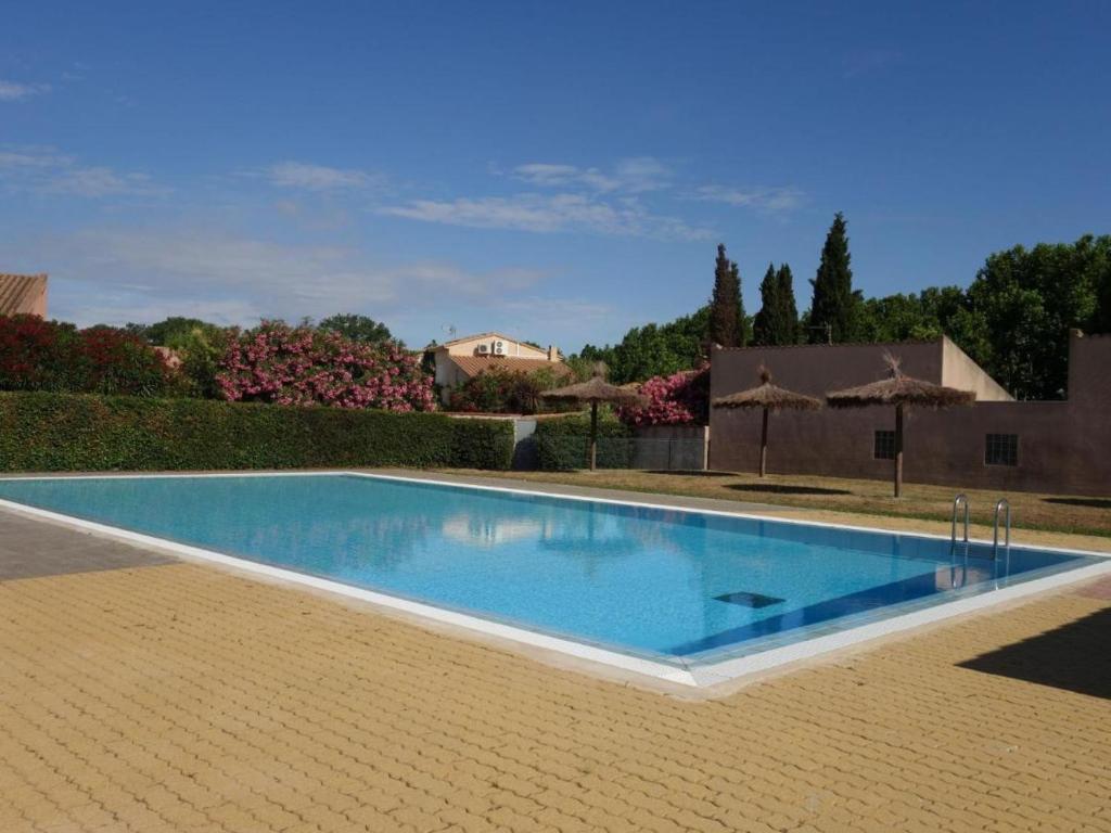 une grande piscine avec de l'eau bleue dans une cour dans l'établissement Logement Coquelicot, à Saint-Cyprien