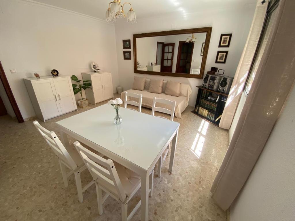 Apartamento Familiar En Barrio Reina Victoria في هويلفا: غرفة معيشة مع طاولة وكراسي بيضاء