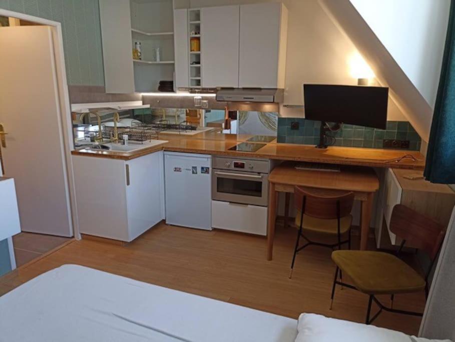 a kitchen with white cabinets and a desk with a computer at Appartement, place Morny. in Deauville