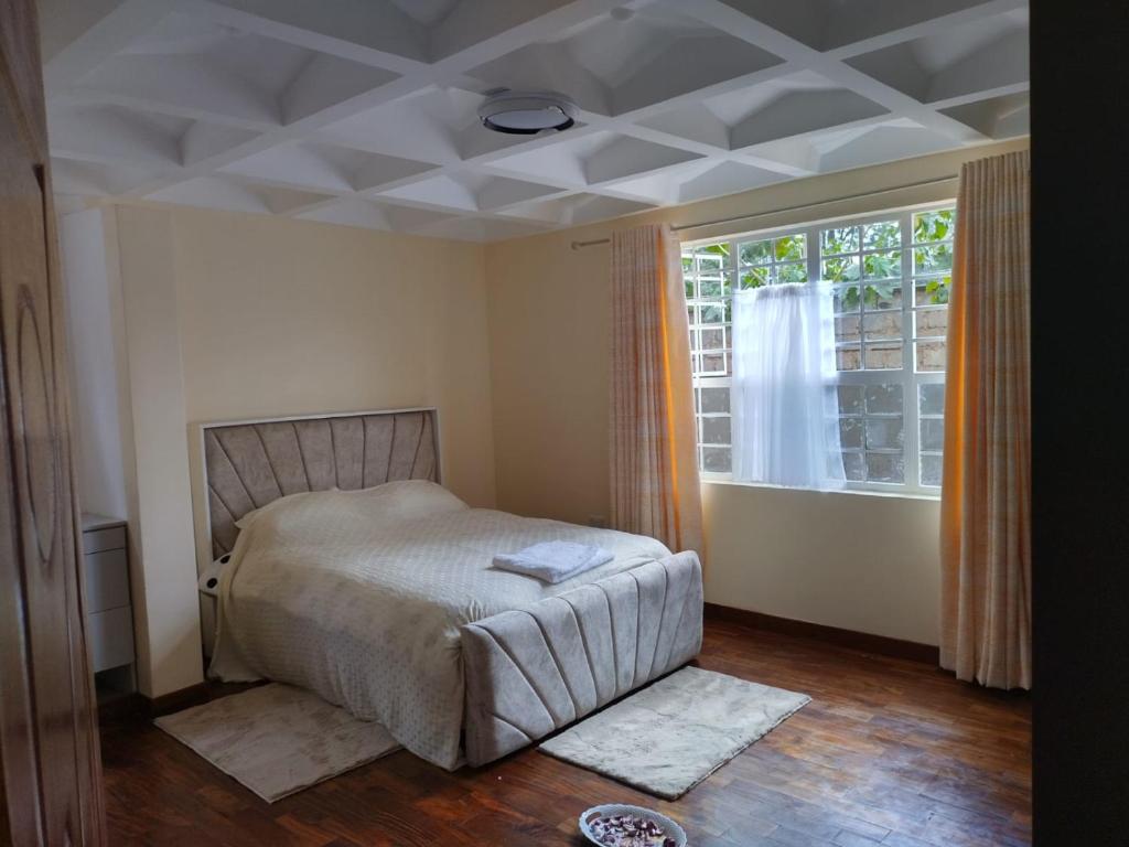 een slaapkamer met een bed en een groot raam bij BomaBnB Holiday Homes in Nairobi