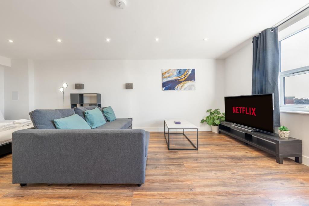 een woonkamer met een bank en een tv bij 4 West London Brand New Loft in Londen