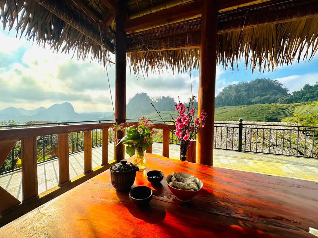 einen Holztisch mit Schalen und Blumen auf dem Balkon in der Unterkunft Hali Home Moc Chau in Mộc Châu