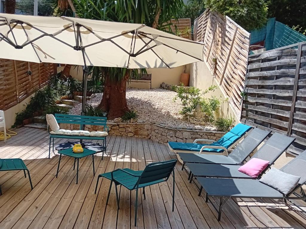 un patio avec des chaises et un parasol sur une terrasse dans l'établissement NICE- GAIRAUT - JARDIN PRIVE- GRAND F1 LUMINEUX-Piscine Collective, à Nice