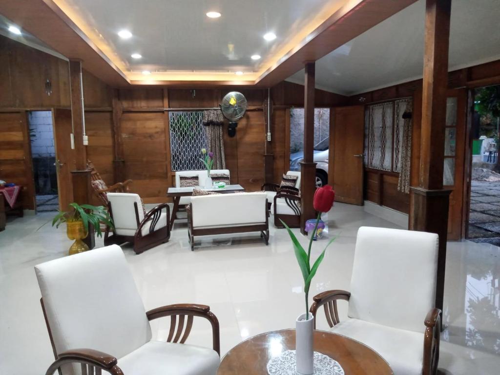 a living room with white chairs and a table at Cahaya Losmen Sragen Syariah in Sragen