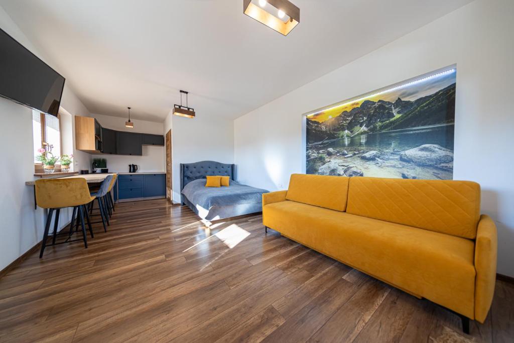 sala de estar con sofá amarillo y cocina en Topór Apartament widokowy z placem zabaw en Kościelisko