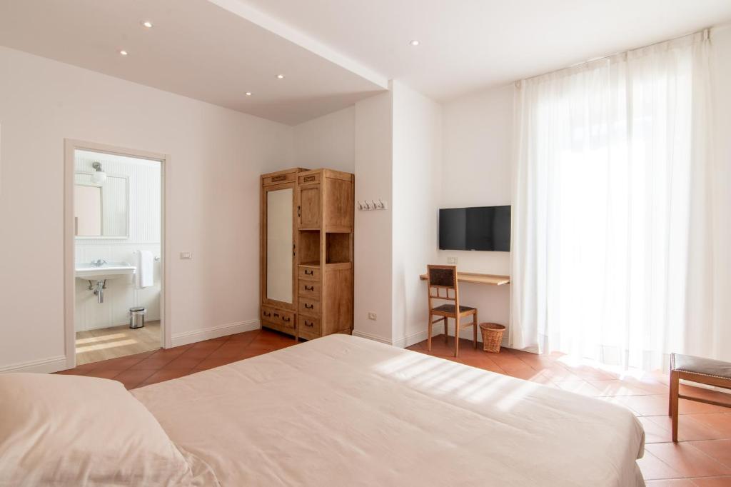 a white bedroom with a bed and a desk at B&B Villa Eden jacuzzi pool in Domaso