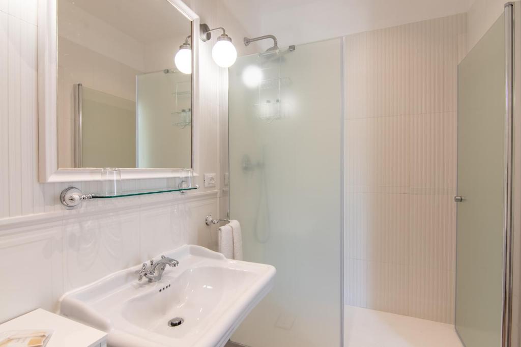 a white bathroom with a sink and a shower at B&B Villa Eden jacuzzi pool in Domaso