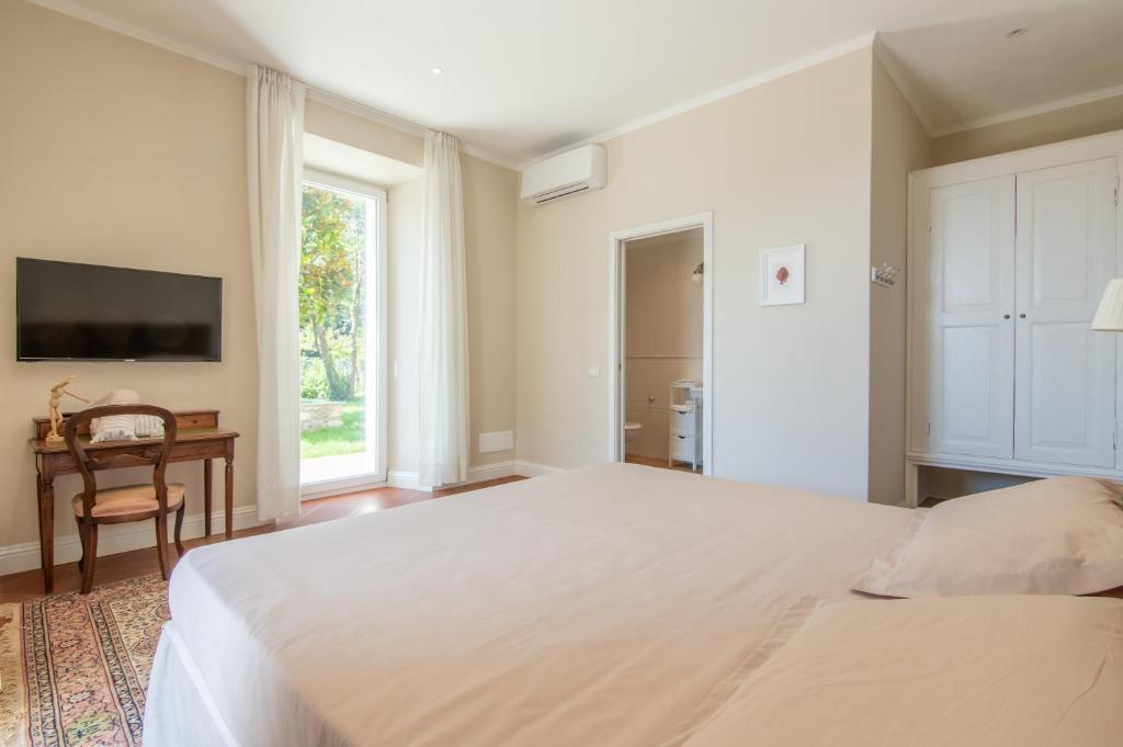 a bedroom with a large white bed and a window at B&B Villa Eden jacuzzi pool in Domaso