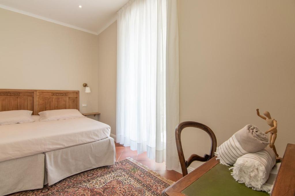 a bedroom with a bed and a chair and a window at B&B Villa Eden jacuzzi pool in Domaso