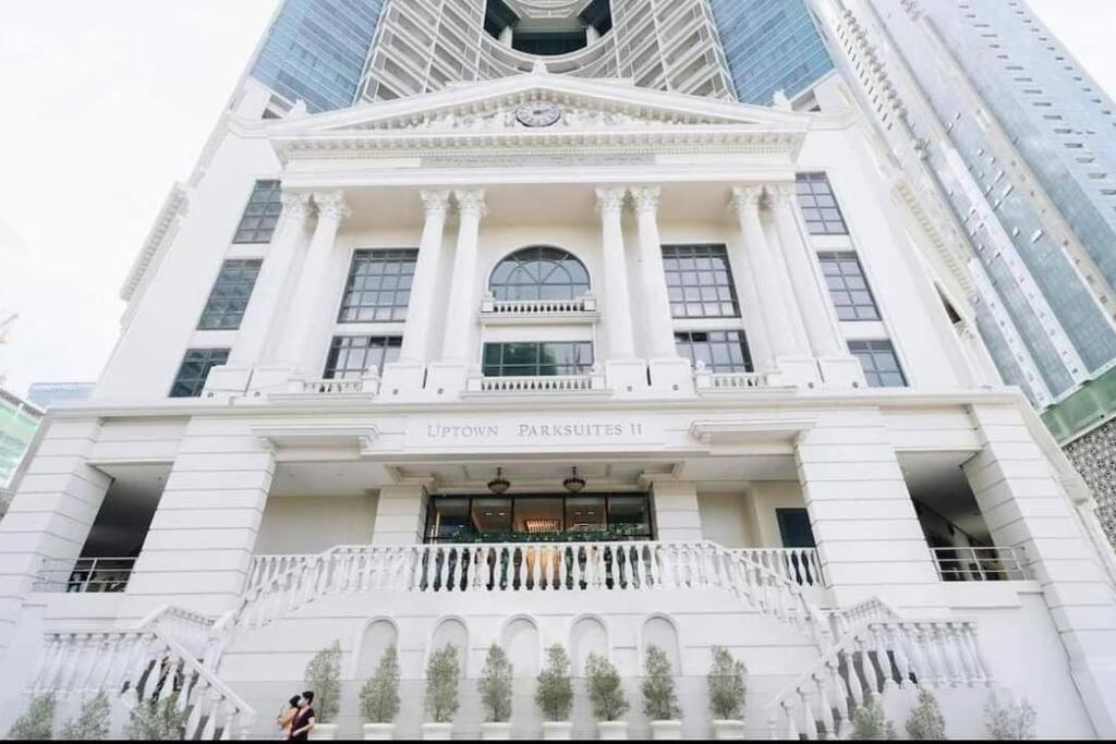 a white building with a balcony and a clock tower at Tranquil Manor at Uptown BGC in Manila