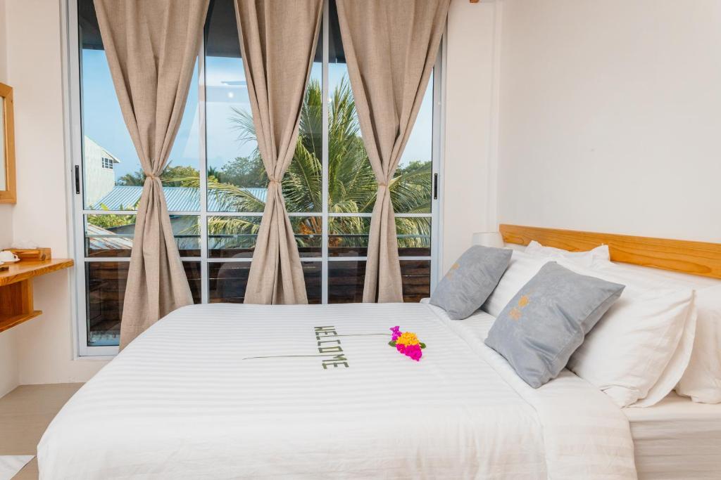 1 dormitorio con 1 cama blanca y ventana en Dhoani Maldives Guesthouse, en Kendhoo