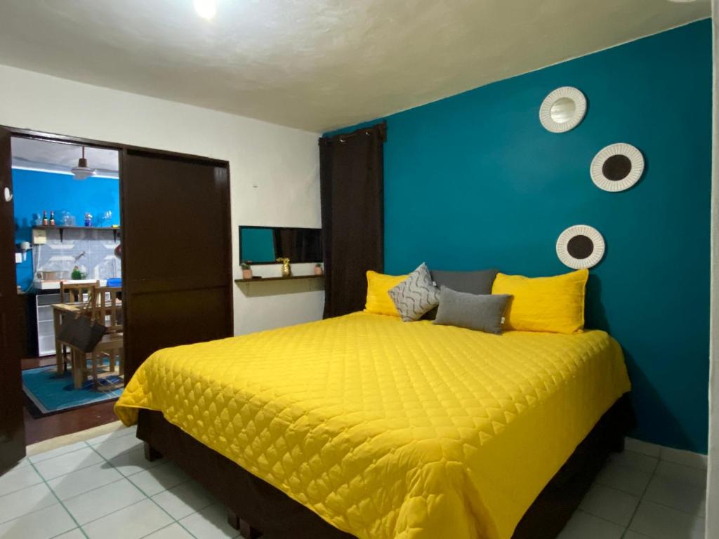 a bedroom with a yellow bed with a blue wall at PANCHITO’S in Isla Mujeres