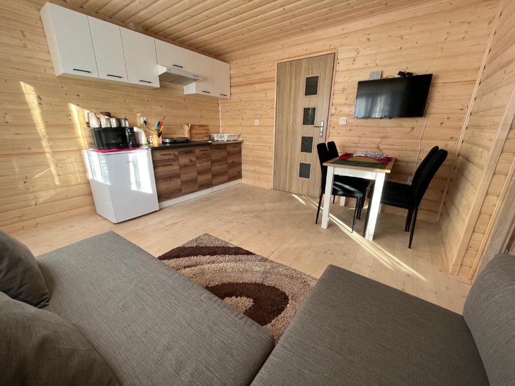ein Wohnzimmer mit einem Sofa und einem Tisch sowie eine Küche in der Unterkunft Domek na górce in Sidzina