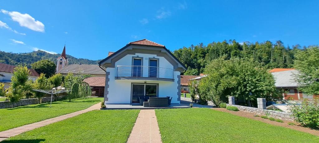 uma casa branca com um alpendre e um relvado em Hisa Haasberg em Planina