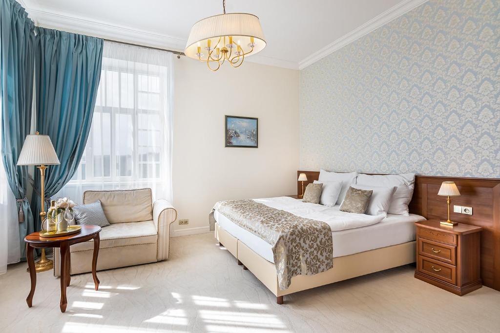 een slaapkamer met een bed, een bank en een raam bij Hotel Katerina in Znojmo