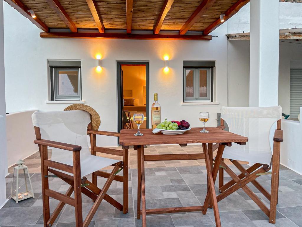 una mesa de madera y sillas con un bol de frutas y copas de vino en Casa Livadia, en Zefiría
