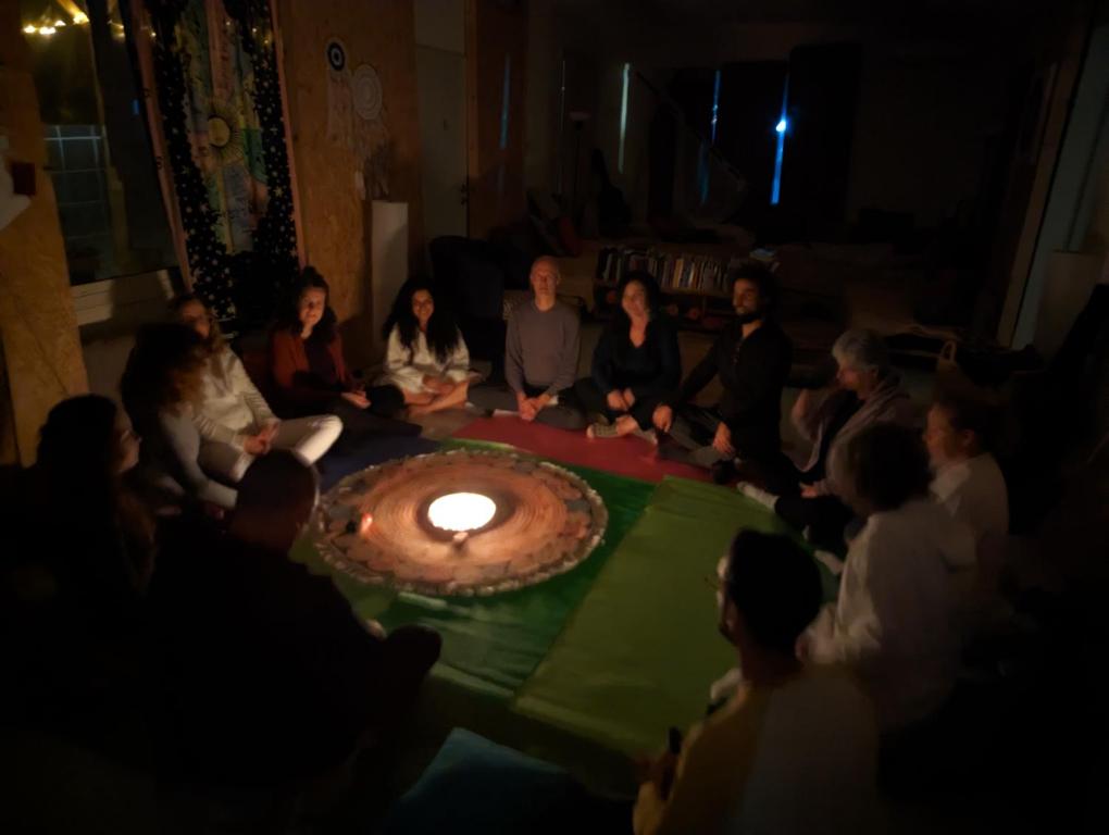 Eine Gruppe von Menschen, die um einen Tisch mit einem Kuchen mit einer Kerze sitzen in der Unterkunft אשראם בכרמל - אכסניה in Dāliyat el Karmil