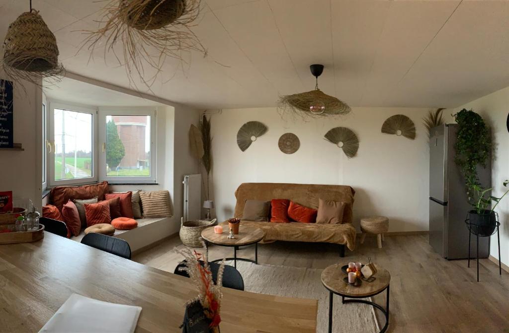 Lodge Vent d’Ouest في جيمبلو: غرفة معيشة مع أريكة وطاولات