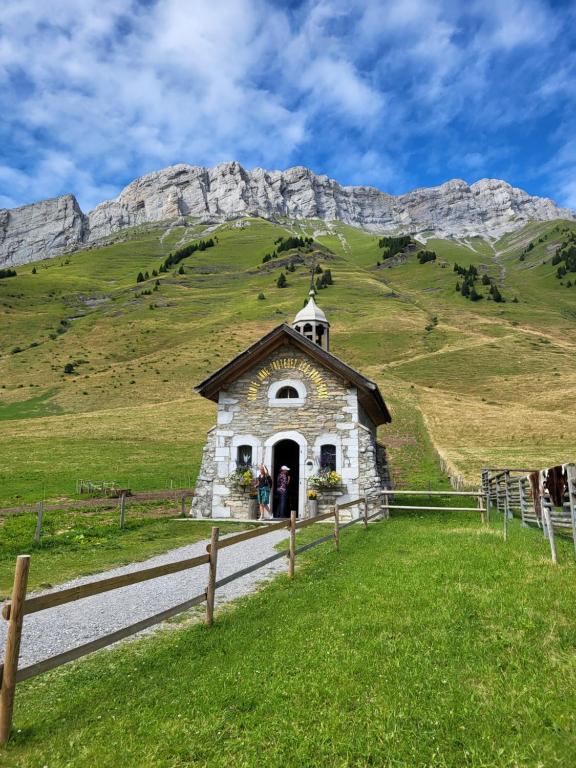 a small church in a field with a mountain at La petite Anfiane in Le Grand-Bornand