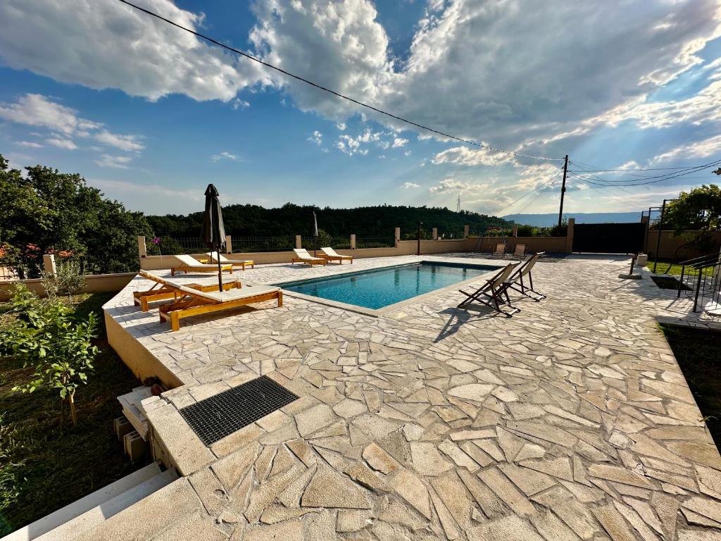 een zwembad op een patio met stoelen bij Sunny village, house with pool in Podgorica