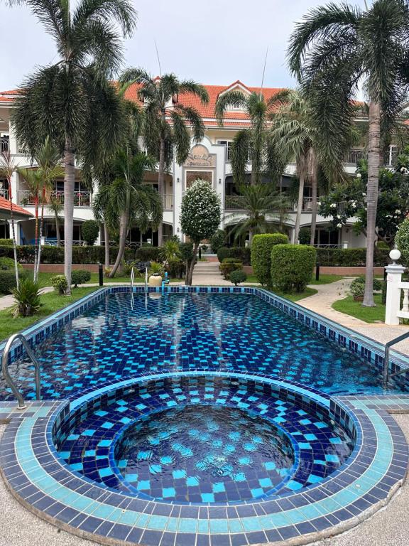 a large swimming pool with blue tiles in front of a building at Wannashan pool villa in Pattaya South