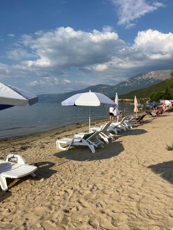a group of lounge chairs and umbrellas on a beach at Tushemisht Lake View Studio Apartment in Pogradec