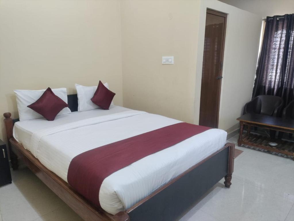 una camera da letto con un grande letto con cuscini rossi e bianchi di VRS Residency a Mysore